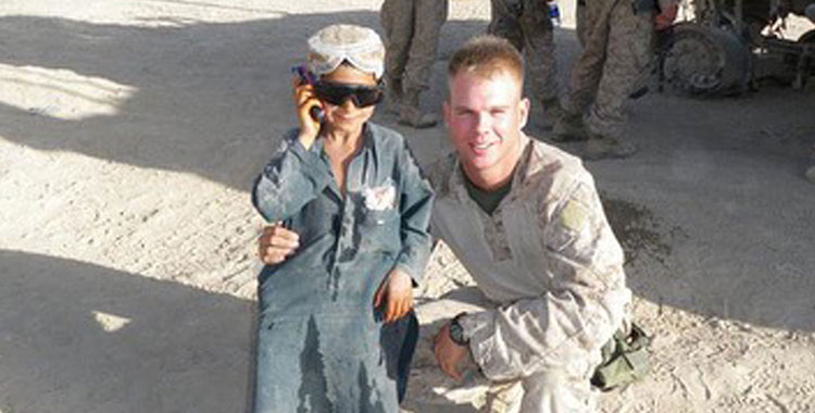 Una foto del capitán Kyle Gettings en uniforme posando con un niño con gafas de sol.